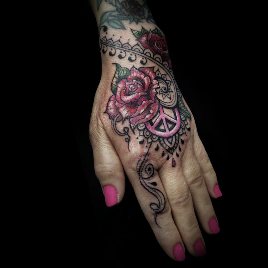 Elegant tattoo featuring intricate roses, a peace symbol, and ornamental patterns, blending floral beauty with bohemian charm