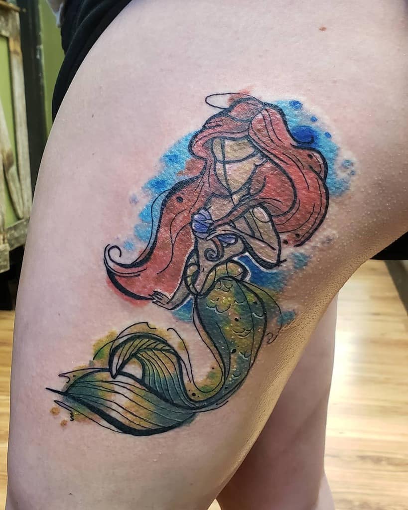 An artistic watercolor-style tattoo of Ariel with flowing red hair, a vibrant green tail, and abstract blue and yellow accents