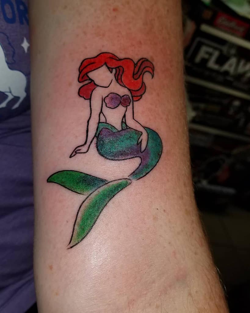 A minimalist tattoo of Ariel with red flowing hair, a purple seashell top, and a shimmering green tail in a simple yet elegant style