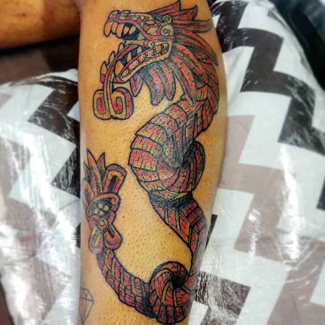 Red and black Quetzalcoatl tattoo featuring the feathered serpent in a coiled design