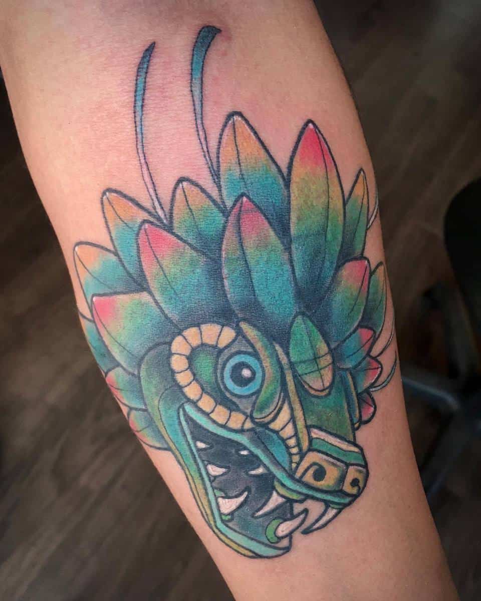 Colorful Quetzalcoatl tattoo featuring a green serpent head with vibrant feather details