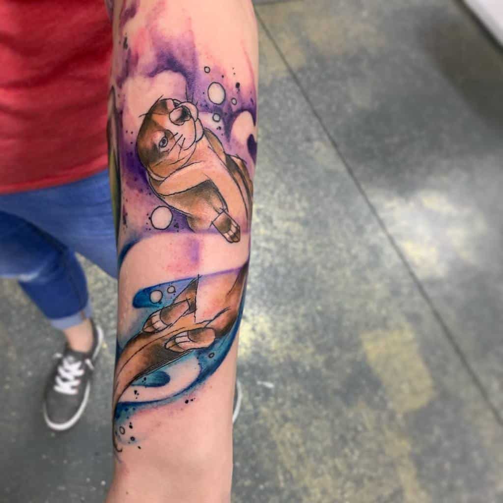 Colorful watercolor-style otter tattoo with shades of purple, blue, and pink, surrounded by bubbles for a playful aquatic theme