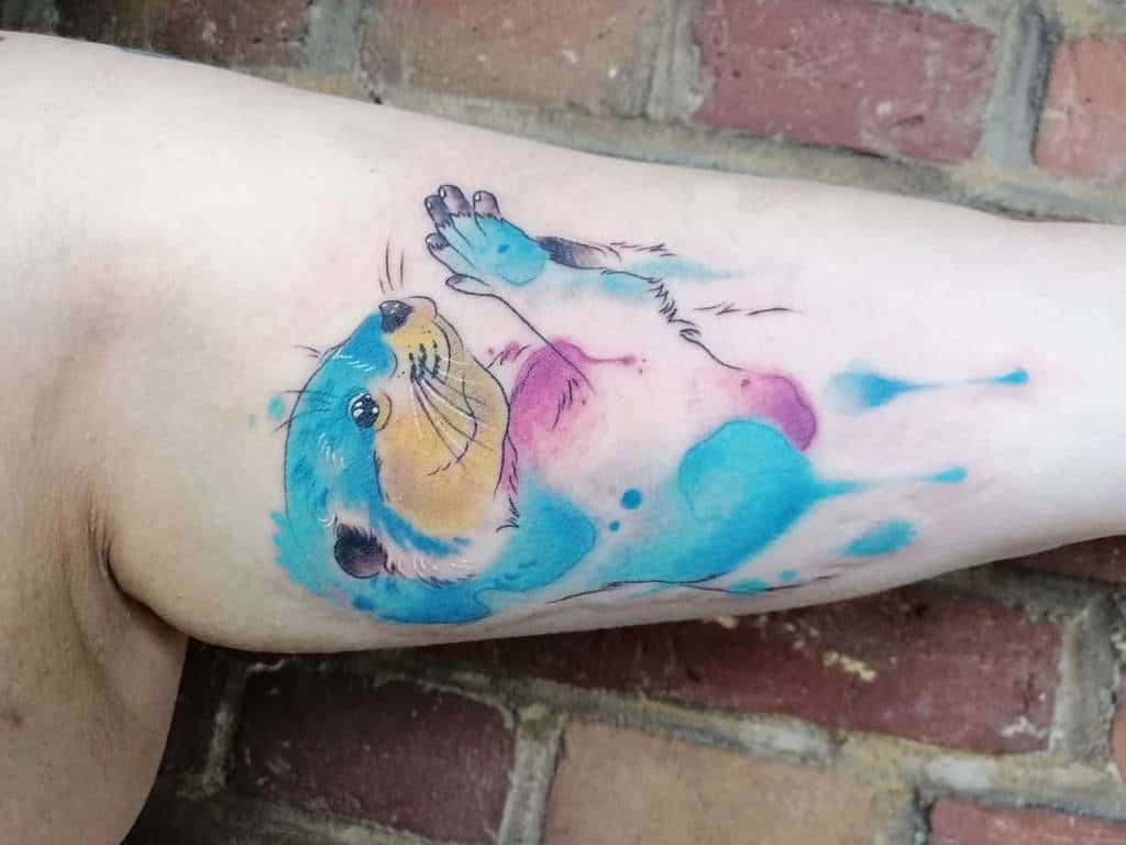 Colorful watercolor otter tattoo on an arm