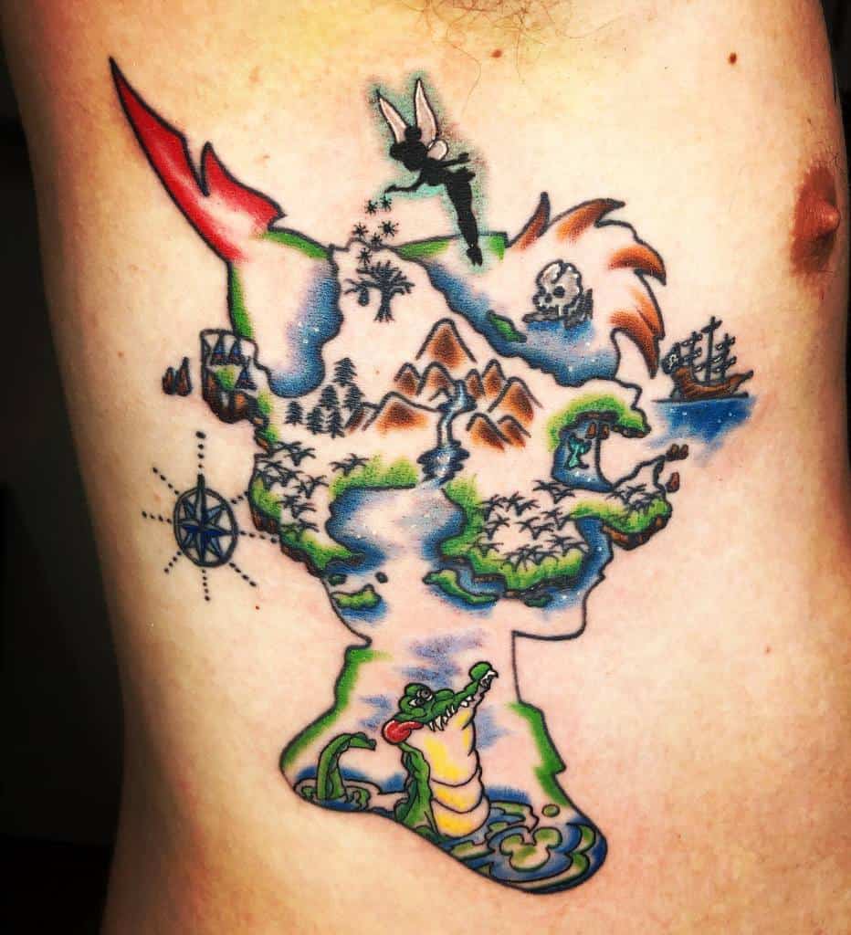 Colorful Peter Pan-inspired tattoo of Neverland in watercolor style, shaped like Peter's head, featuring Tinkerbell, a compass, and a crocodile