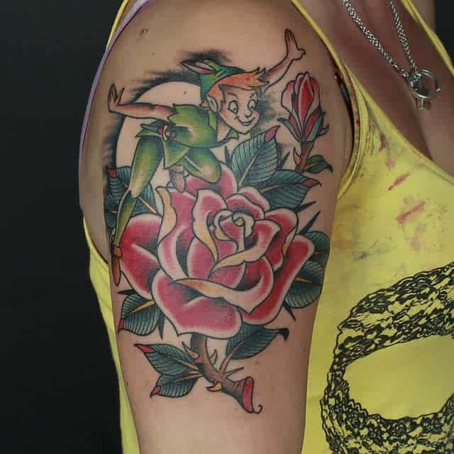 Bold and colorful tattoo of Peter Pan playfully flying over a large red rose, blending classic and neo-traditional styles