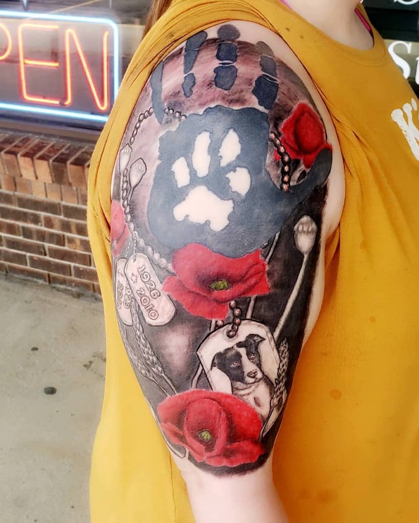 Half sleeve tattoo of paw print, red poppies, dog tags, and spoon on woman's upper arm