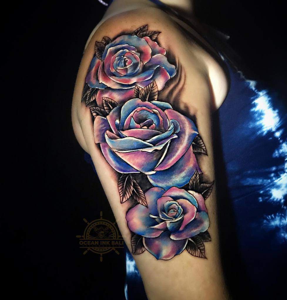 Arm tattoo of three blue and pink roses with leaves