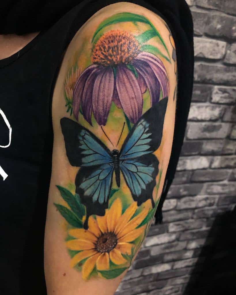Tattoo of a blue butterfly and vibrant flowers on an arm