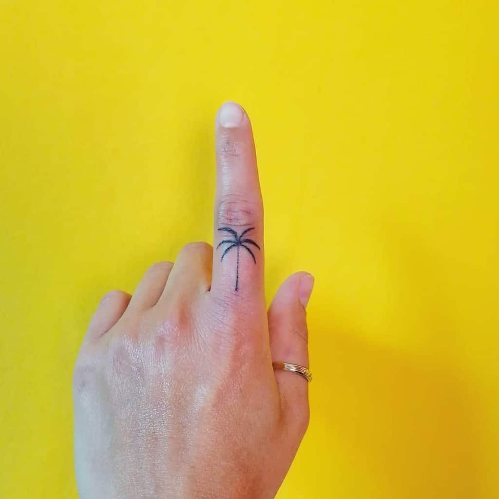 Hand with palm tree tattoo on pinky finger