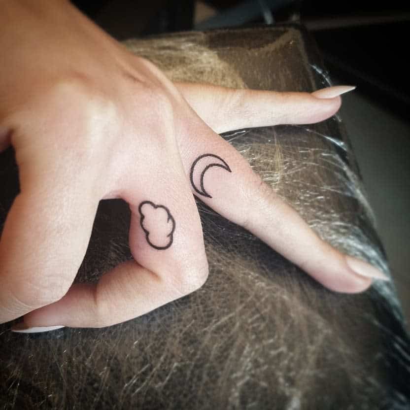Hand with cloud and crescent moon tattoos on fingers