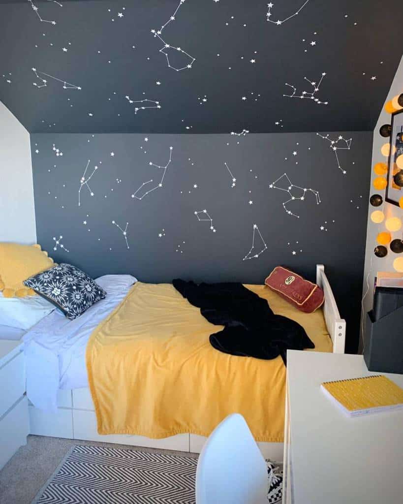 Kids' bedroom with constellation wall art, cozy yellow bedding, and a study desk.