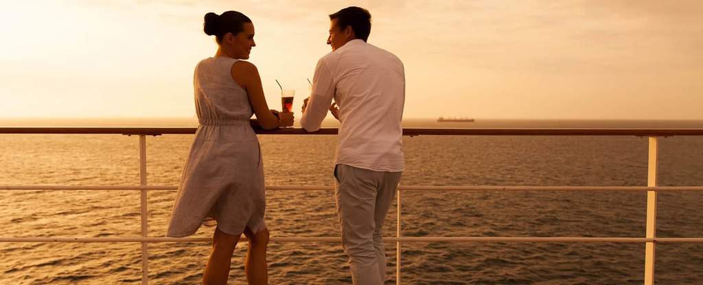 Couple On Deck Of Cruise Ship at Sunset