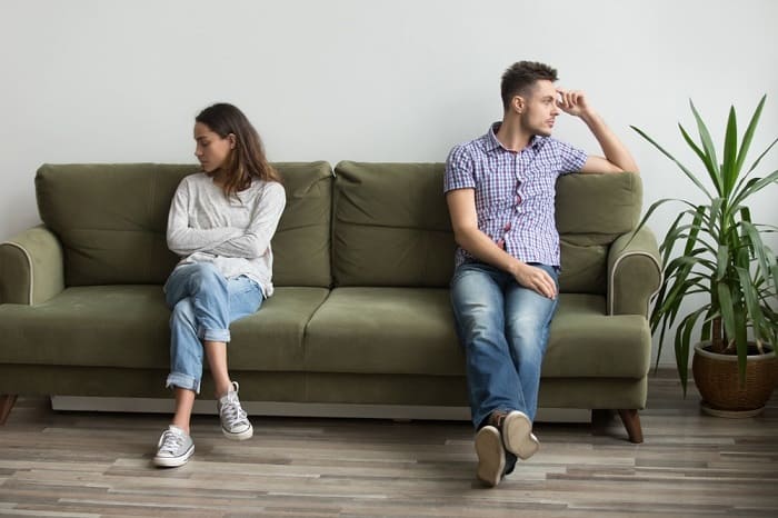 Couple sitting on opposite ends of sofa looking in different directions