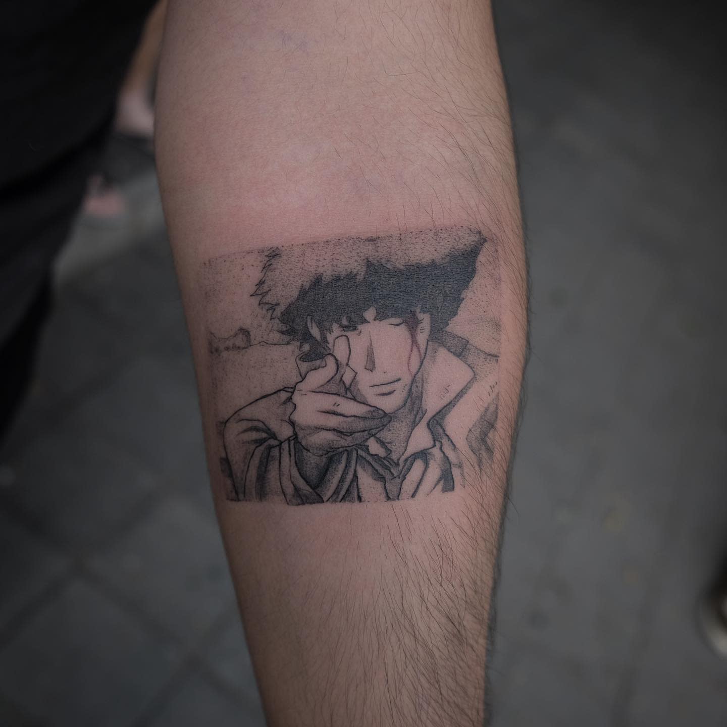 Small tattoo of Spike Spiegel from Cowboy Bebop, mimicking a finger gun gesture within a rectangular frame