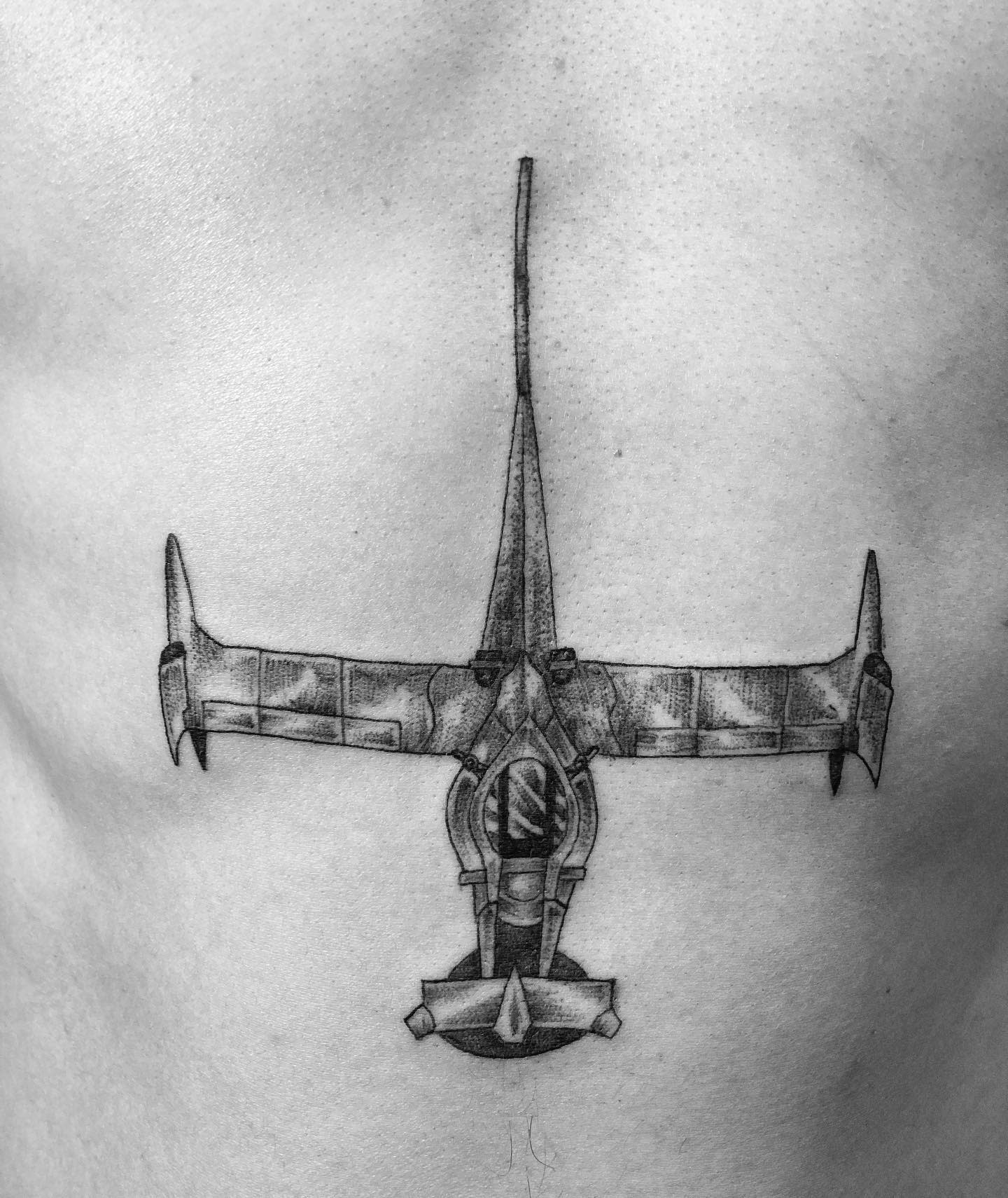 Detailed black and gray tattoo of the Swordfish II spaceship from Cowboy Bebop, centered on the chest