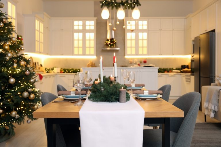 Modern kitchen with luxury lighting, a Christmas tree, candles, and a festive dining table set for a holiday meal