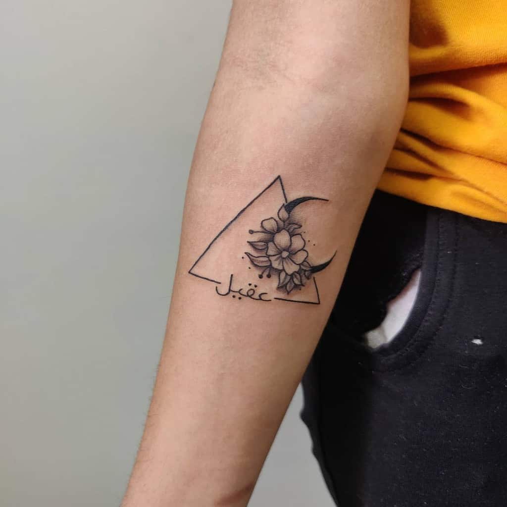 Arm tattoo featuring intricate flowers, a crescent moon, and Arabic script elegantly enclosed within a triangle