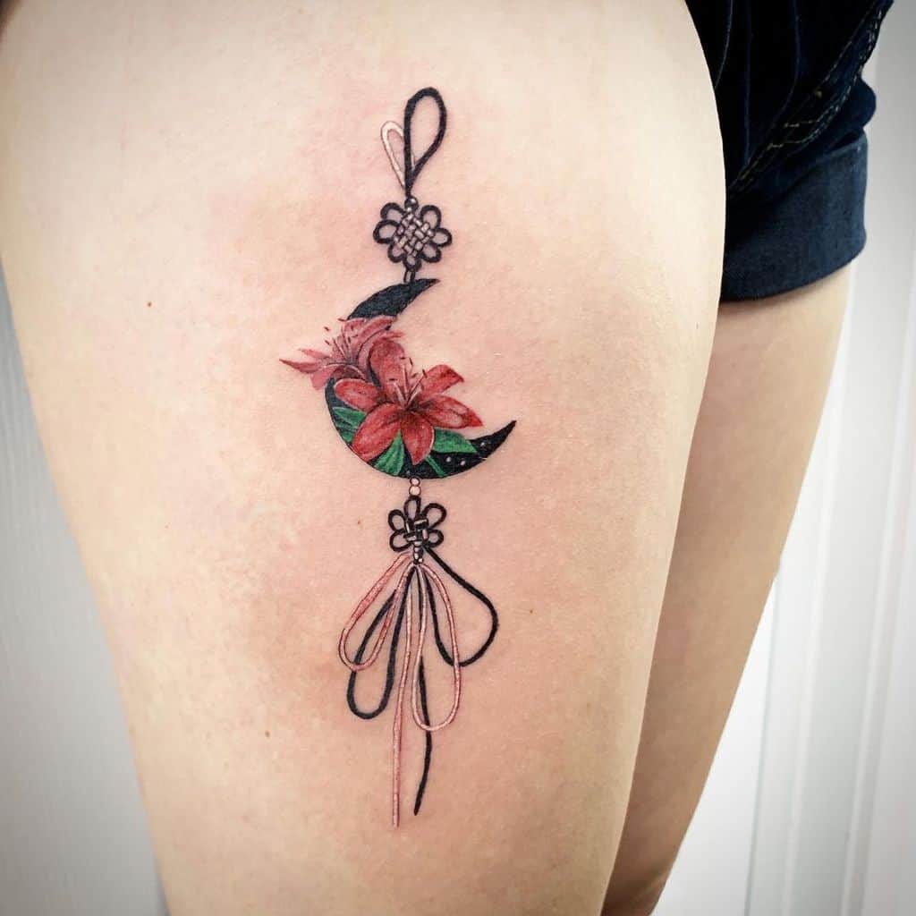 Floral and crescent moon tattoo with decorative lines gracefully etched on the upper thigh