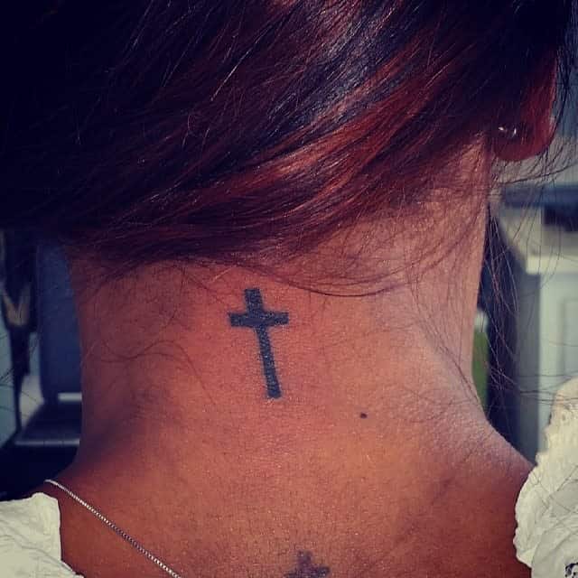 A black cross tattoo on the back of the neck