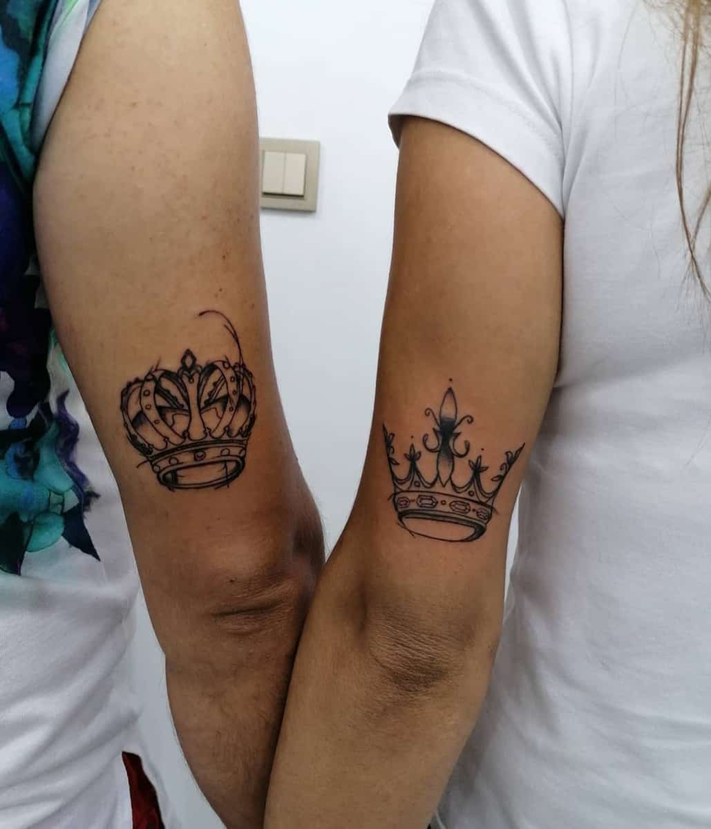 Matching crown tattoos on the arms of two people standing side by side