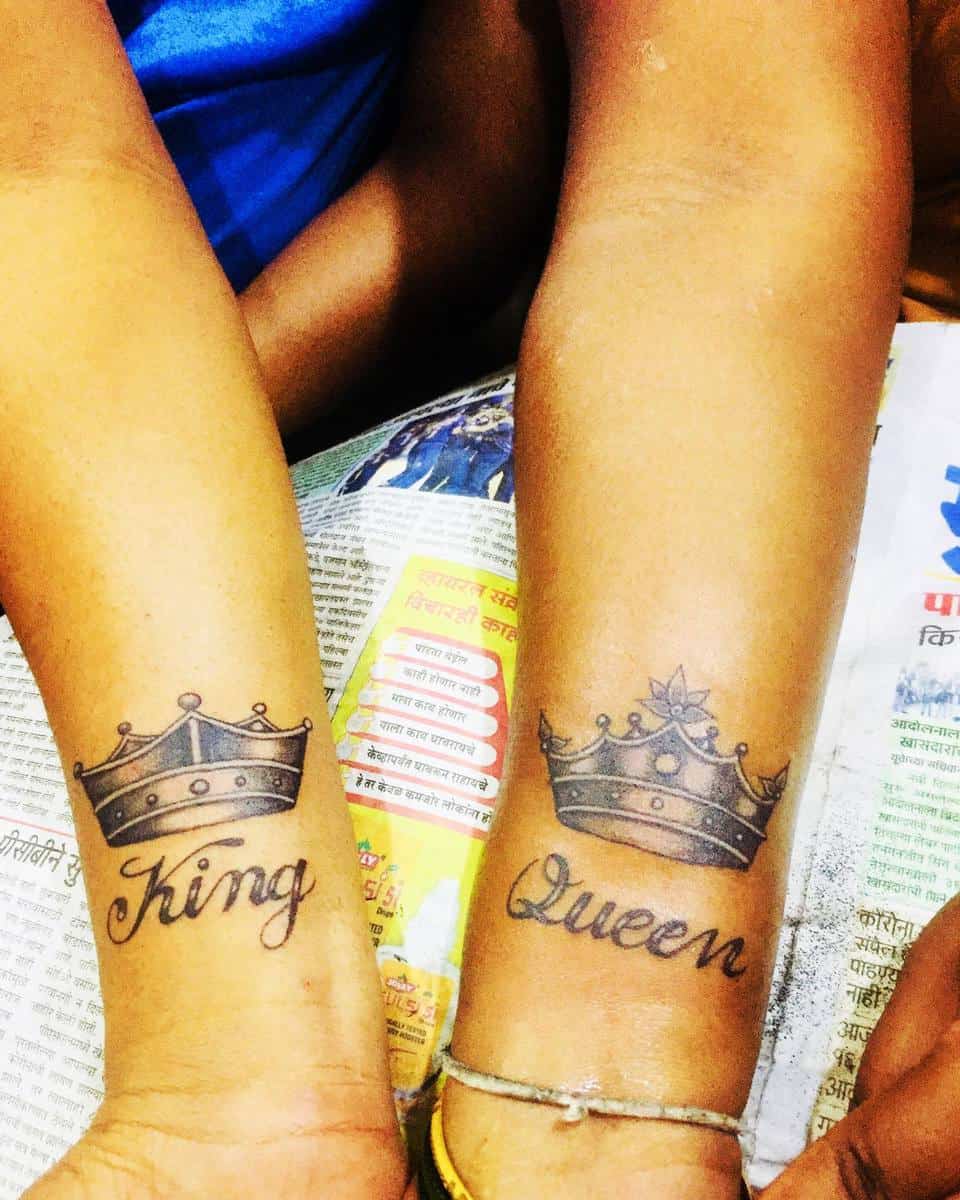 Matching "King" and "Queen" crown tattoos on wrists of two people