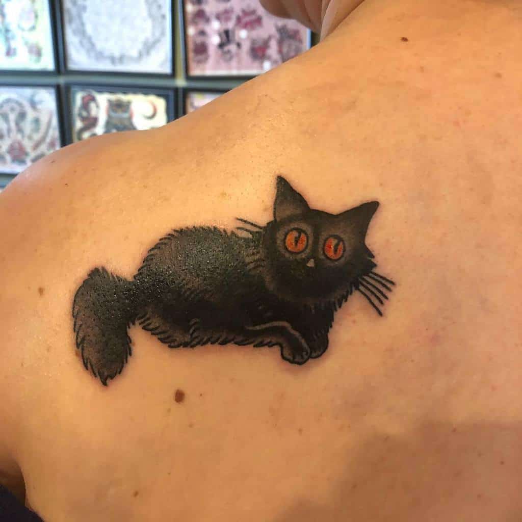 Tattoo of a sleek black cat with piercing red eyes on a person's shoulder blade