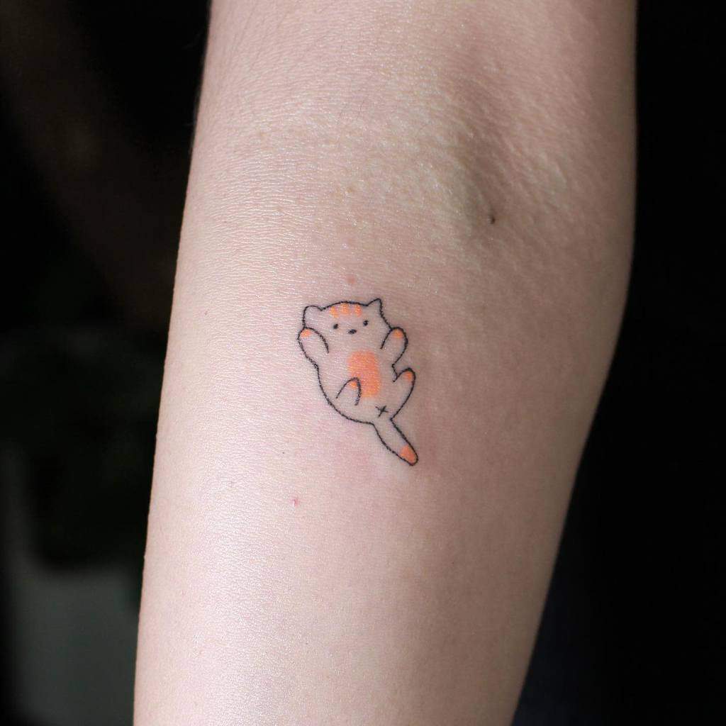 Simple tattoo of a small orange and white cat lounging gracefully on its side on someone's arm
