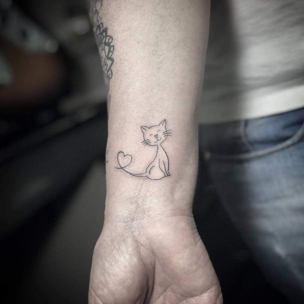 Simple cat tattoo with a heart-shaped tail on a wrist