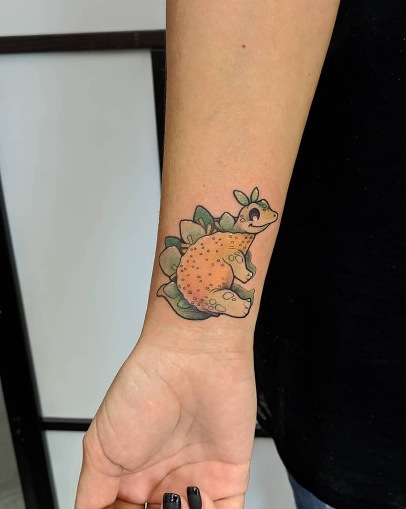 Tattoo of a cute cartoon dinosaur on a wrist