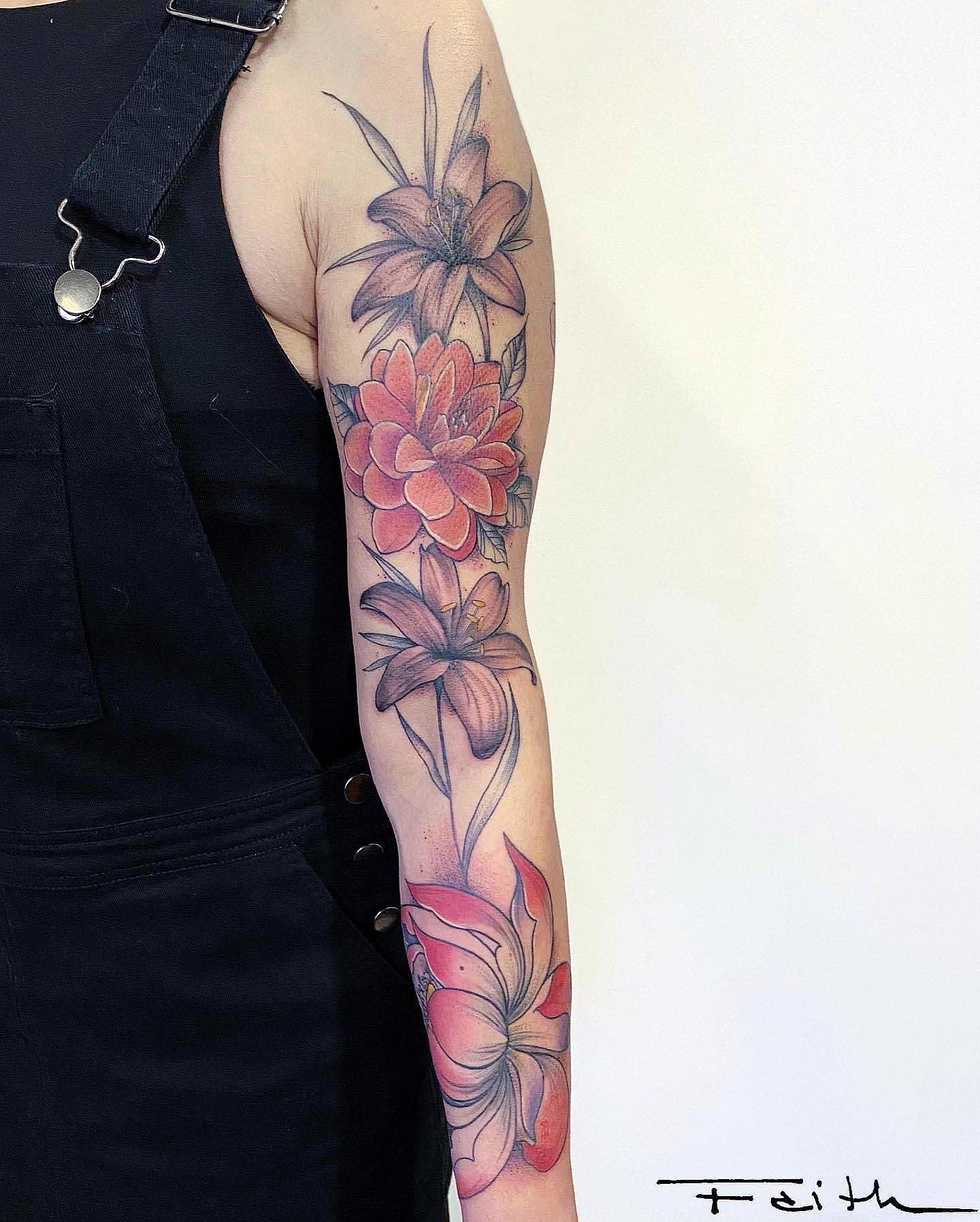Arm tattoo featuring detailed lotus, dahlia, and lily flowers in shades of pink and red