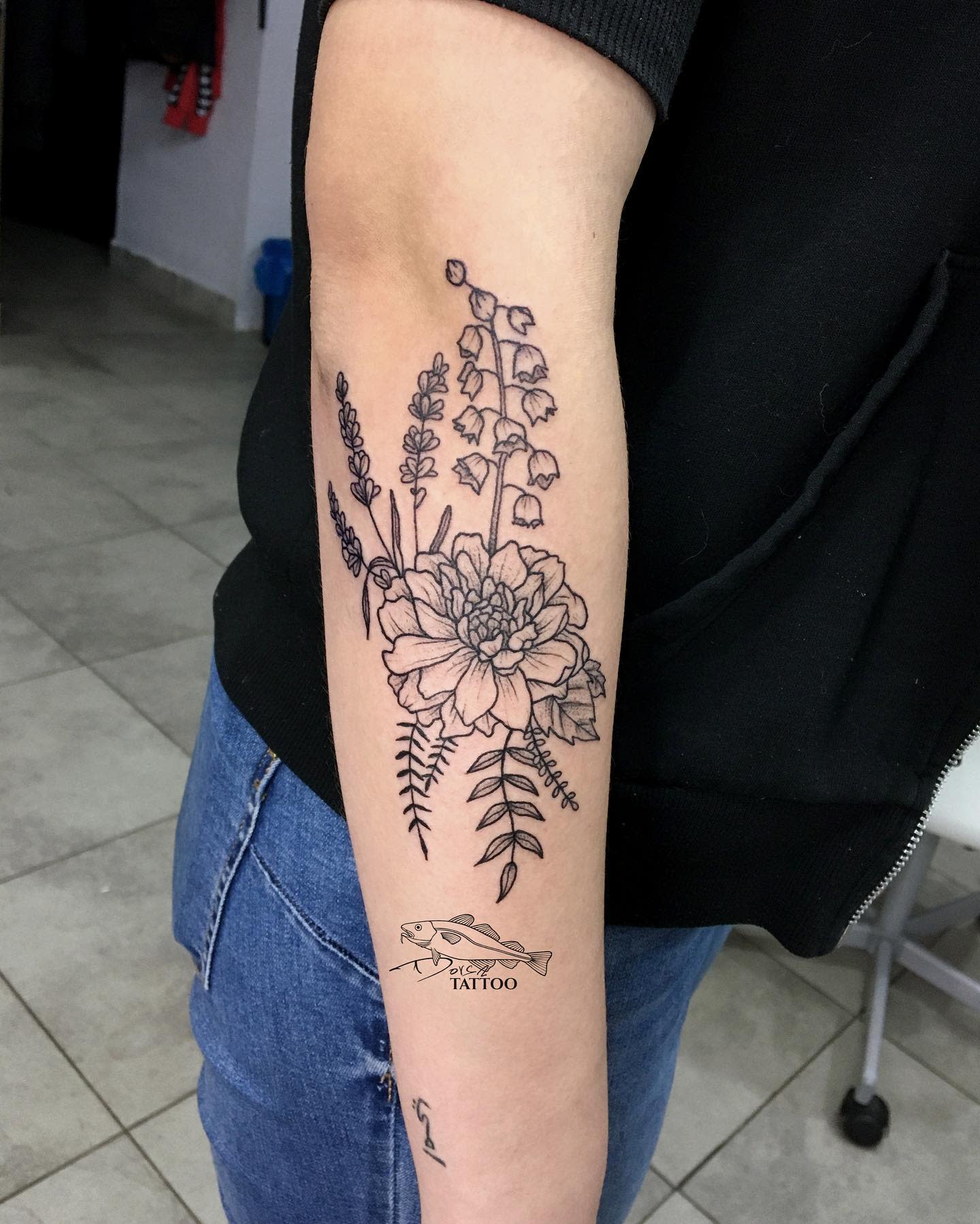Black and grey forearm tattoo with a detailed dahlia, lavender, and botanical elements