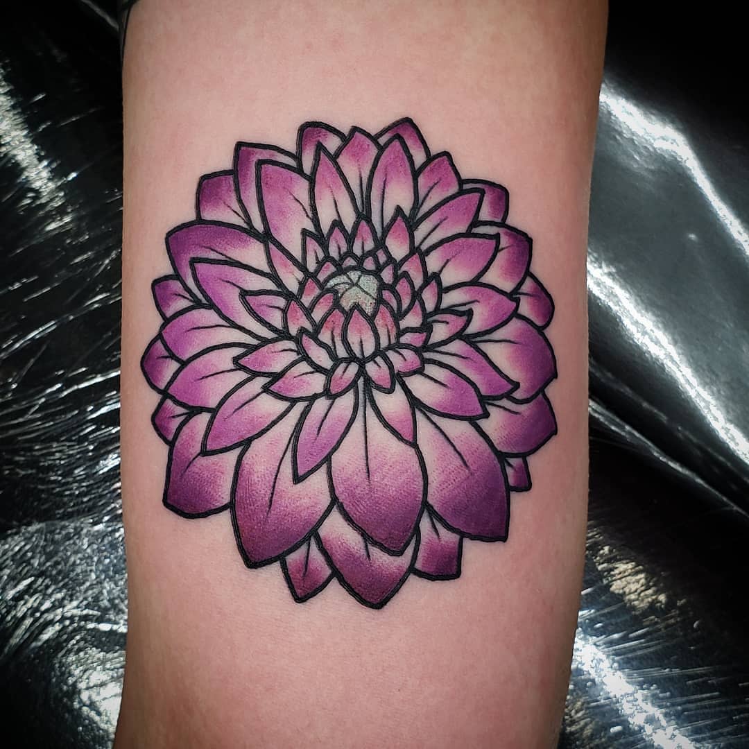 Vibrant purple dahlia tattoo with bold black outlines and gradient shading on the petals
