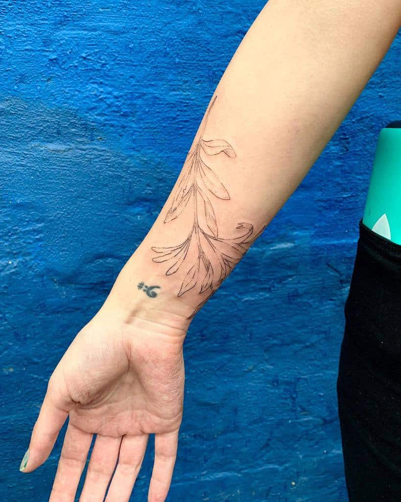 Minimalist honeysuckle tattoo on the forearm with fine, delicate linework and soft floral details