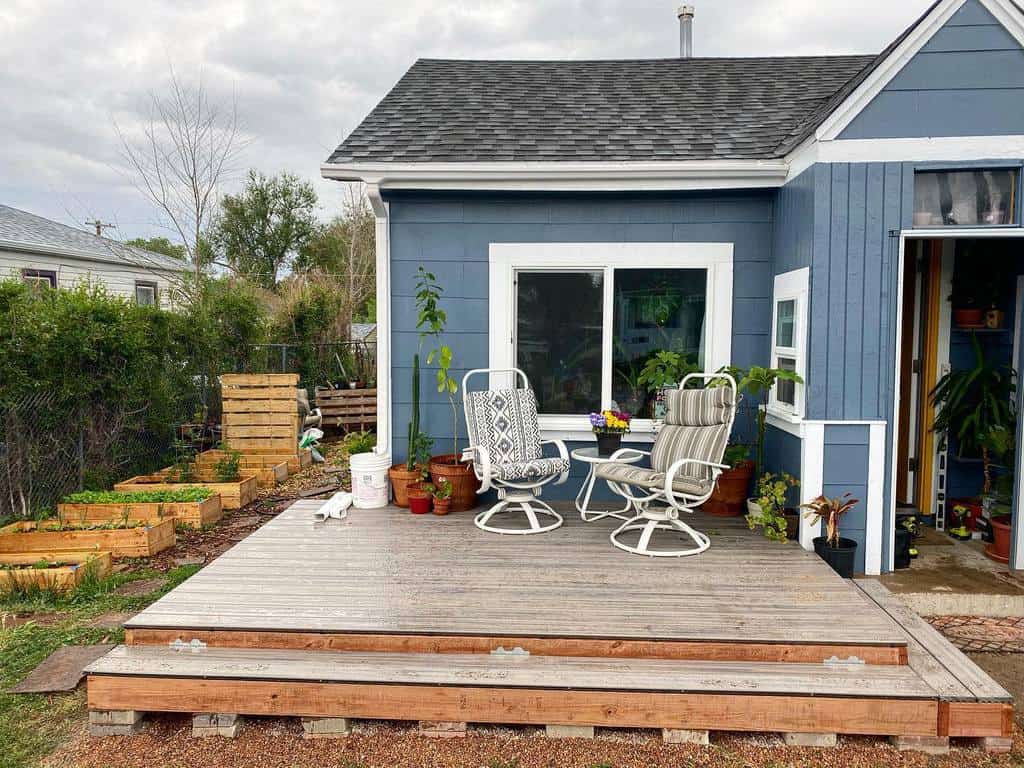 blue house wood deck two white seats planter garden