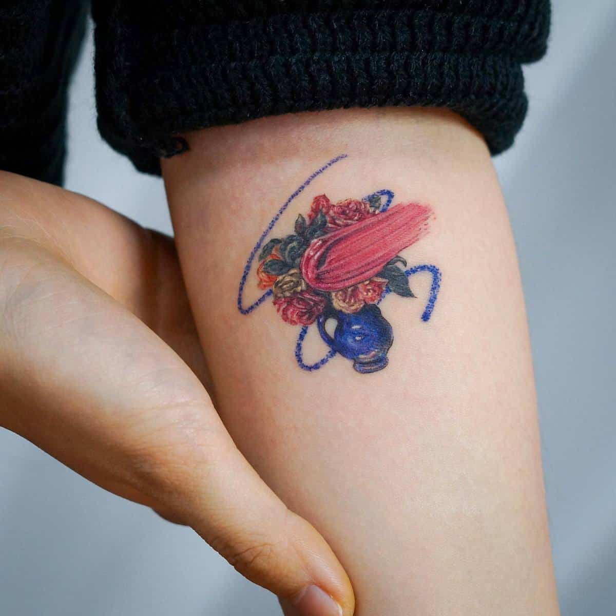 Tattoo of a blue vase with flowers on a forearm