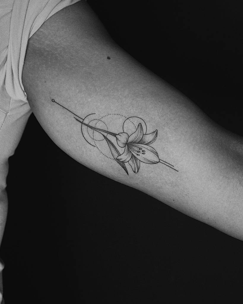 Minimalist black and grey tattoo of a lily with geometric linework and dot detailing, creating an elegant and modern floral design