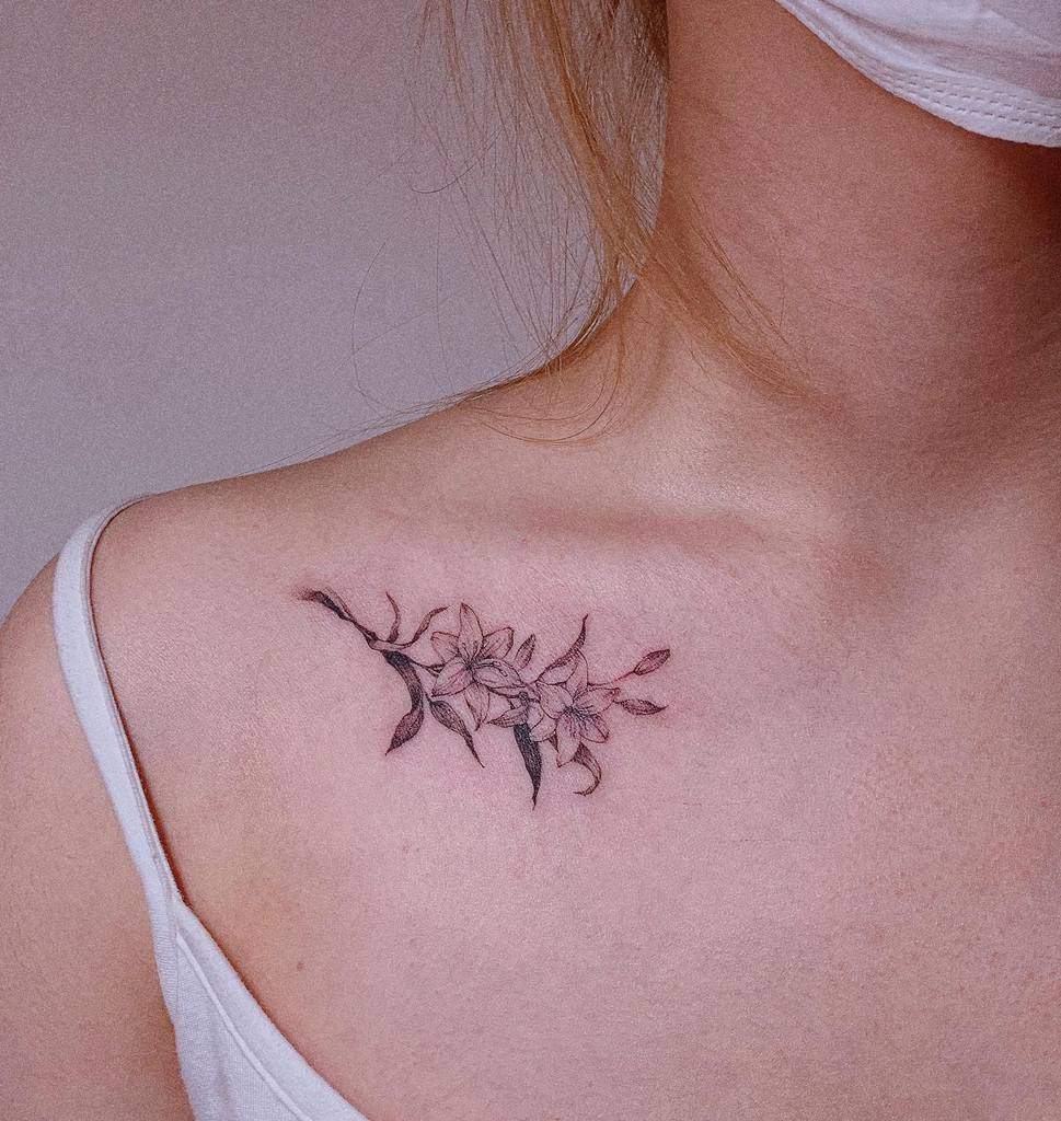 Delicate fine-line tattoo of a lily branch with soft shading, creating an elegant and feminine floral design