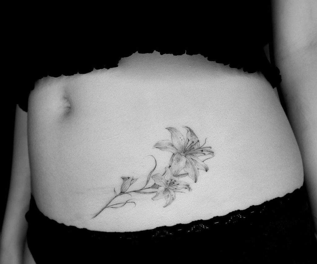 Delicate black and grey tattoo of two blooming lilies with fine line details