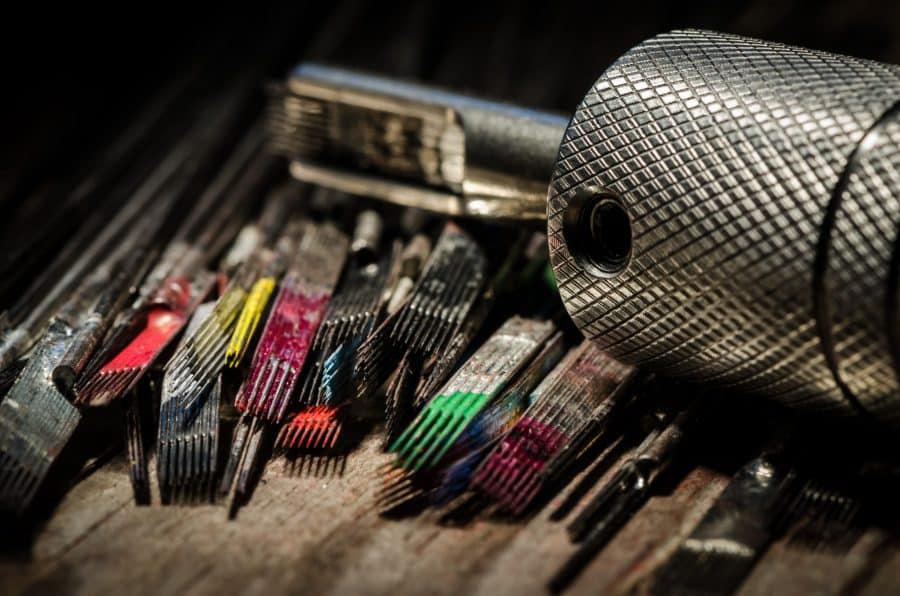 Tattoo supplies featuring needle cartridges with colorful inks and a tattoo machine grip suitable for single needle precision