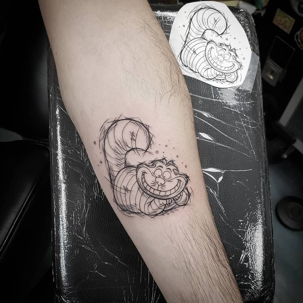A minimalist Cheshire Cat tattoo in a sketch-like design, featuring its iconic grin and swirling tail