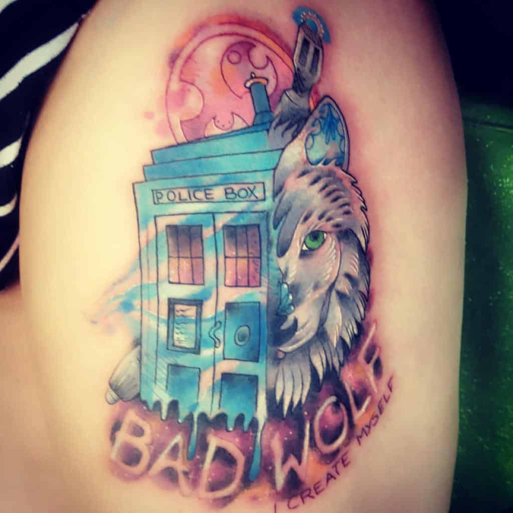 Colorful tattoo from Doctor Who with a TARDIS, a wolf's face, and the phrase 'BAD WOLF. I CREATE MYSELF' beneath a pink moon
