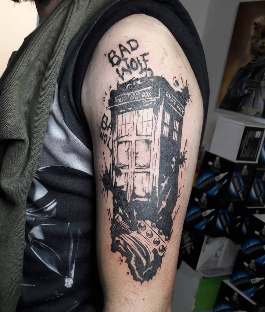 Monochrome tattoo of the TARDIS from Doctor Who, appearing worn and distressed with 'BAD WOLF' written above it