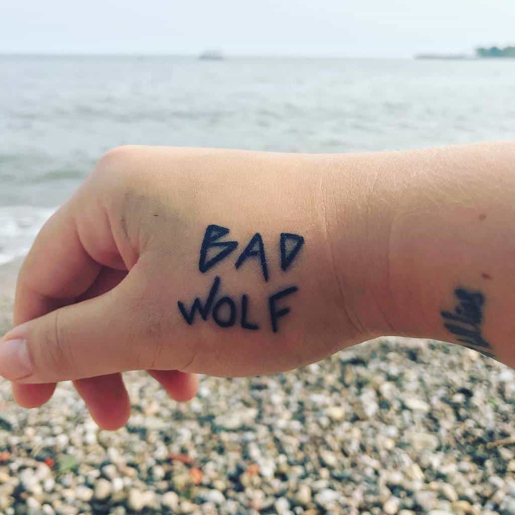 Minimalist 'BAD WOLF' tattoo in bold, handwritten-style, referencing the TV show 'Doctor Who'