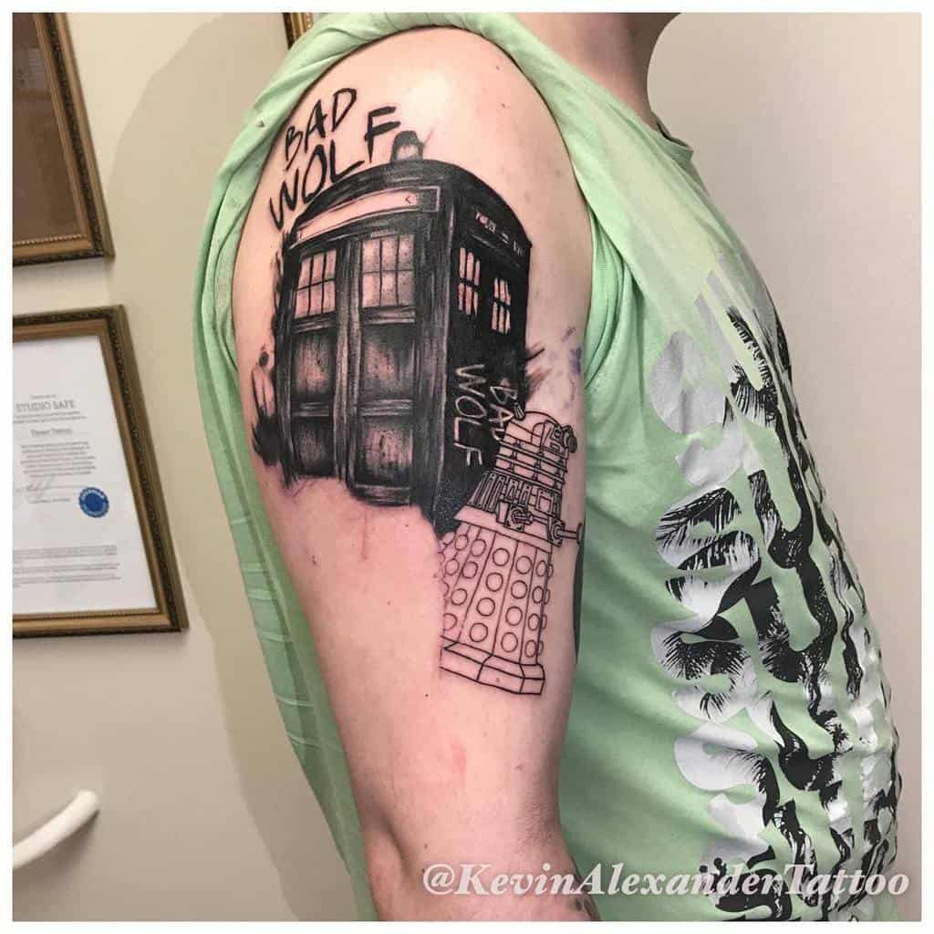 Dramatic tattoo featuring the TARDIS and a Dalek from 'Doctor Who', with 'BAD WOLF' written in bold above the scene, all rendered in black and grey ink