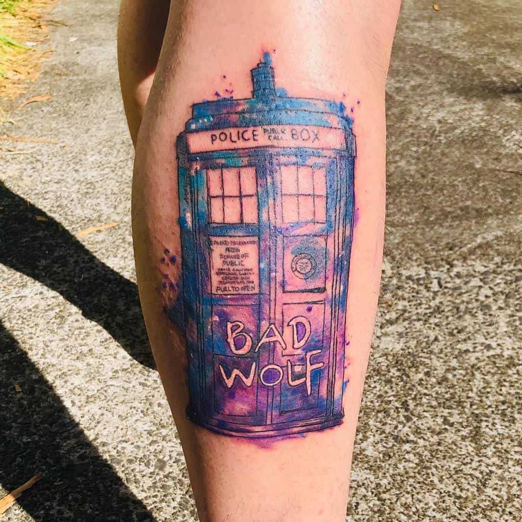 Colorful watercolor-style tattoo of the TARDIS from 'Doctor Who', featuring a vivid blue and purple hue with 'BAD WOLF' written on the door