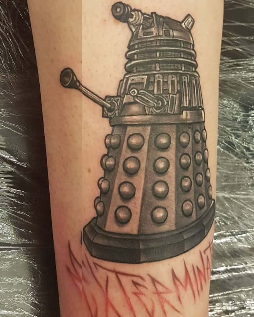 Black and grey tattoo of a Dalek from 'Doctor Who', with detailed shading and the word 'EXTERMINATE' inked boldly below