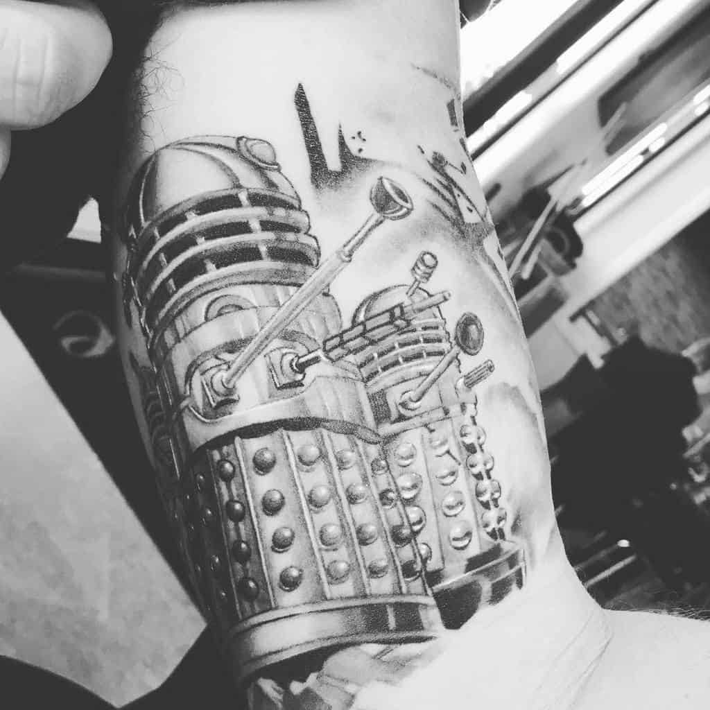 Monochrome tattoo depicting two Daleks from 'Doctor Who', rendered in a detailed black and grey style with dramatic shading