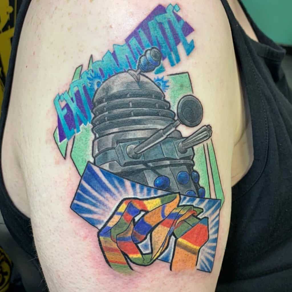Colorful tattoo depicting a Dalek from 'Doctor Who' in a vivid, comic book style, with the word 'EXTERMINATE' in bold, multicolored letters above and a stylized abstract design below