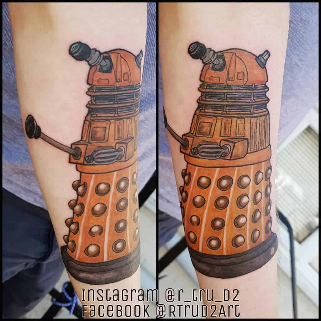 Realistic tattoo of a Dalek from 'Doctor Who', rendered in shades of orange and brown, capturing the iconic design and detail of the character