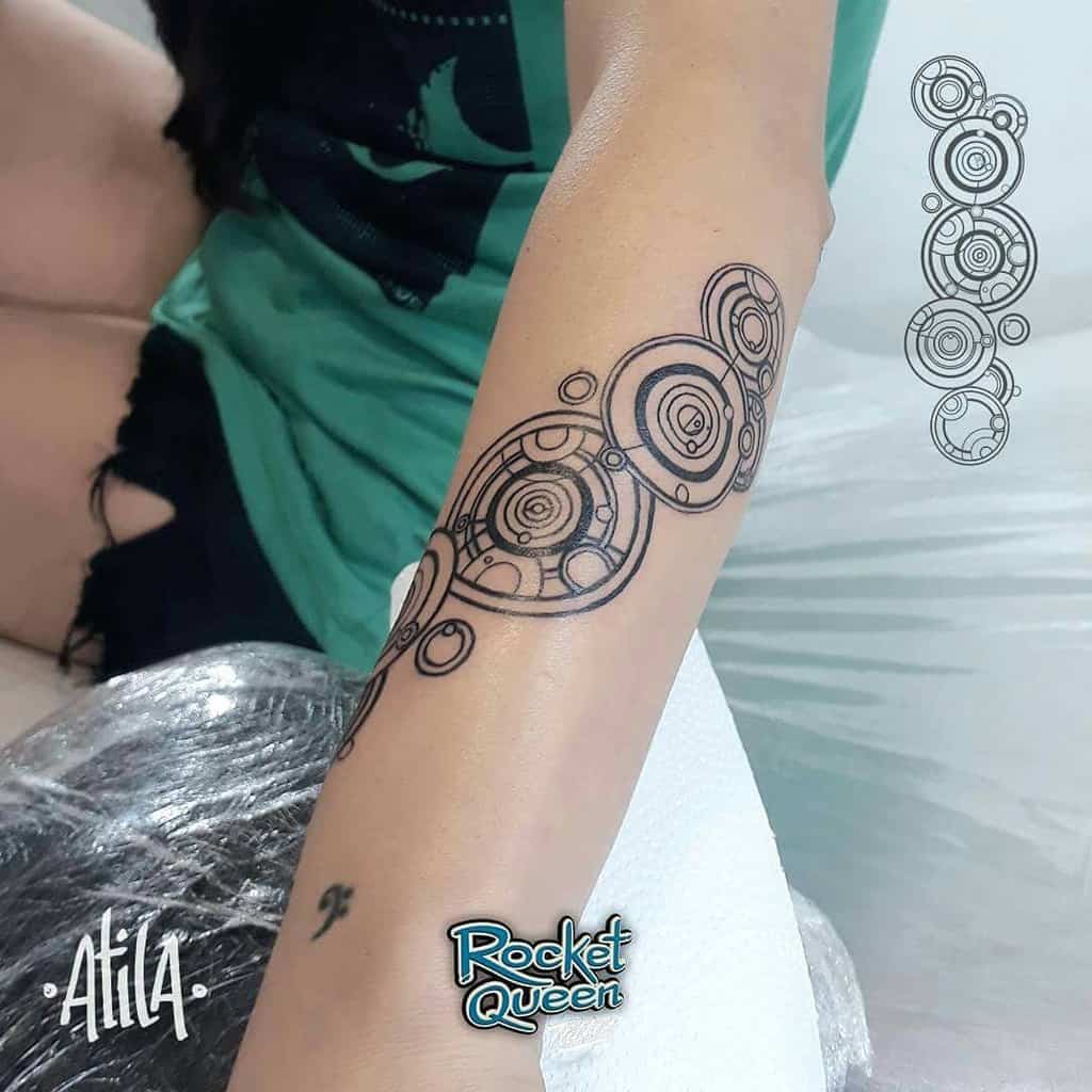 Tattoo featuring a line of intricate Gallifreyan script from 'Doctor Who', composed of circular designs in black ink